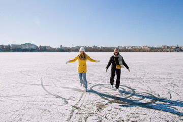 Women ice skating on frozen lake enjoying winter day