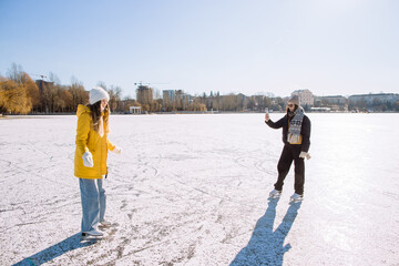 Friends ice skating capturing memories on a frozen lake