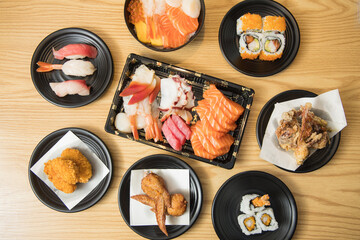 A colorful Japanese spread with sashimi, sushi rolls, chirashi, fried chicken, grilled wings, and soft shell crab on black plates.