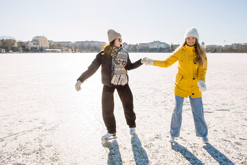 Two young women enjoying winter ice skating on frozen lake