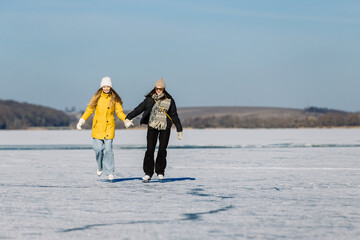 Fototapeta premium Young women ice skating on frozen lake