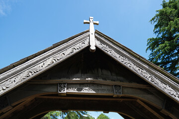 Detail of Historic Wooden Lychgate and Cross Against Blue Sky