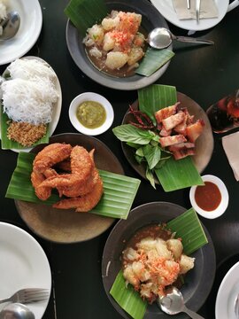 Top view of northeast Thai food on dark background,​ fried chicken wings, pamelo salad, Thai rice noodles in Thailand