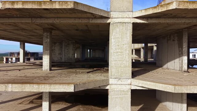 A large, empty structure stands abandoned, its concrete framework exposed. Nature encroaches silently, reflecting the peaceful surroundings and whispering stories of forgotten plans.