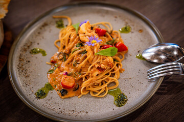 A fusion pasta dish topped with seafood, cherry tomatoes, basil, and aromatic herbs. Served on a modern ceramic plate, the vibrant colors and rich texture create an elegant and appetizing presentation
