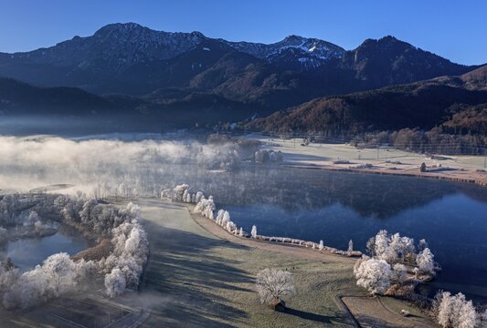 Aerial view of a lake in front of mountains in winter, hoarfrost, morning light, view of Herzogstand and Heimgarten, Lake Kochel, foothills of the Alps, Bavaria, Germany