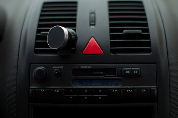 Fototapeta premium Closeup car dashboard center console view showing hazard button and radio controls, muted lighting, matte plastic vents, functional knob and analogue
