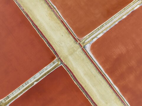 Saline ponds at the Bonanza salt works near Sanl&uacute;car de Barrameda. The red colour depends on the level of salinity and is directly caused by the algae Dunaliella salina and brine shrimp. Aerial view. Drone shot. C&aacute;diz province, Andalusia, Spain