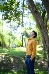 An office man stands in a green park breathing fresh air with a calm and relaxed mood