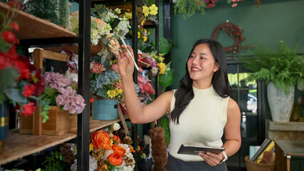 Florist business owner managing flower stock in her shop with a digital tablet