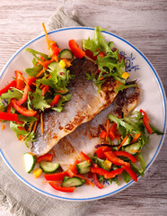 Fried fish fillet with salad on plate