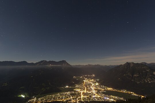 Night shot of an illuminated town in front of mountains, starry sky, Garmisch-Partenkirchen, Zugspitze on the left, Kramer on the right, Bavarian Alps, Upper Bavaria, Bavaria, Germany