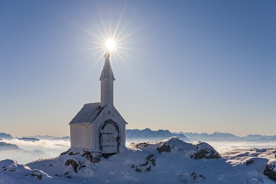 Small chapel with sun star on snowy mountain peak, backlight, winter, chapel on Hochgern, Chiemgau Alps, Upper Bavaria, Bavaria, Germany