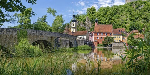 Panoramic view of the ancient stone bridge over the river Naab with the church tower of St Michael and the leaning tower of the old town hall in the background, Kallmünz, Upper Palatinate, Bavaria, Germany