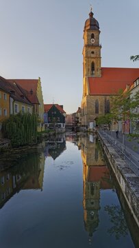 The setting sun bathes everything in warm light and reflects the Basilica of St Martin in the River Vils, Amberg, Upper Palatinate, Bavaria, Germany