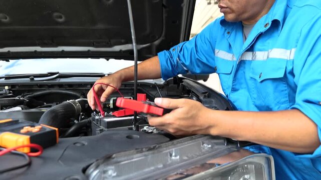 Service man to check car battery voltage, technician using multimeter, auto electrical check, vehicle maintenance service, close up diagnostic tool
