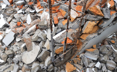 Pile of construction demolition rubble with broken concrete, bricks, and exposed rusty rebar. Industrial texture background illustrating destruction, renovation, waste, and building materials.