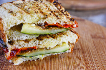 Close-up of a grilled vegetable panini filled with zucchini, roasted peppers, and melted cheese on rustic toasted bread. Ideal for menus, healthy food ads, vegan content, and culinary marketing.