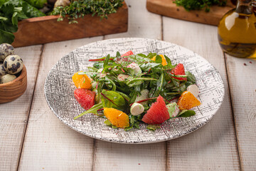 Fresh green salad with watermelon orange segments and creamy dressing served on a patterned plate