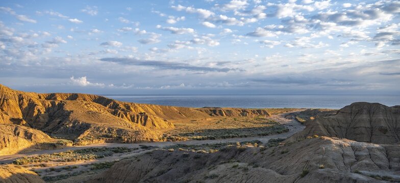 Landscape of eroded hills at sunrise, badlands, Issyk Kul Lake in the background, Canyon of the Forgotten Rivers, Issyk Kul, Kyrgyzstan