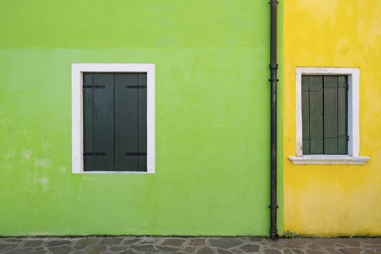 Green and yellow house facade with windows with closed shutters, colourful houses on the island of Burano, Venice, Veneto, Italy