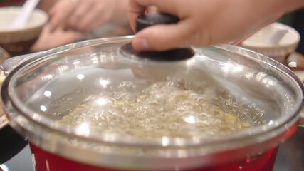 4K Close-up image of vigorously boiling broth in stainless steel hot pot,  intensity and heat of traditional Asian hot pot cooking. 