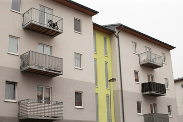 Apartment building facade with yellow stripe and balconies, contemporary accent color, editorial listing vibe, clean lines, stucco