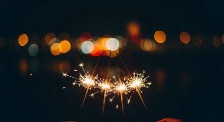 Golden sparklers burning brightly in the dark night sky, held by hands against a beautiful bokeh background of colorful city lights for celebration