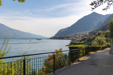 Panoramic view of Limone sul Garda, Lombardy, Italy. A picturesque pedestrian path runs along the blue waters of Lake Garda.