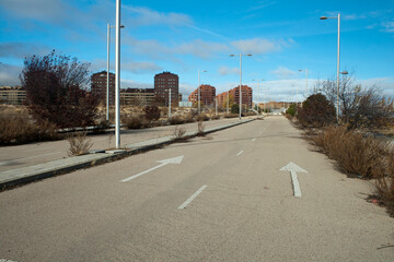 Empty Urban Road Leading to Modern Residential Buildings Under Blue Sky