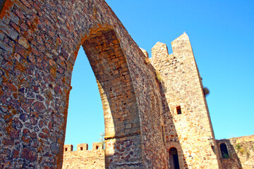 Ancient Stone Archway and Castle Walls Against Blue Sky