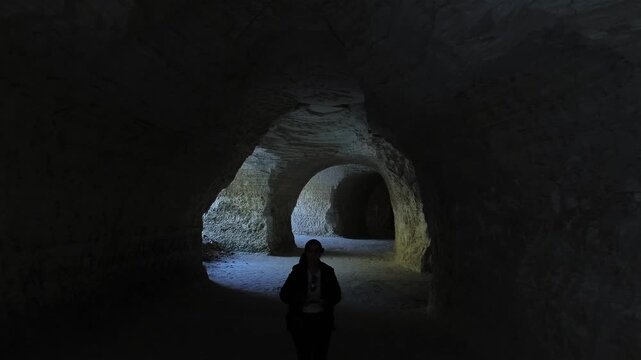 Female tourist silhouette walking inside rocky cave passage in chalk mines in Tlaxcala state of Mexico zoom in camera movement