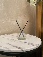Clear reed diffuser on round marble side table