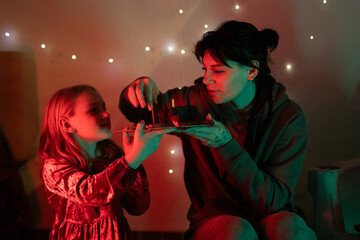 Mother and daughter celebrating birthday with sweet cake