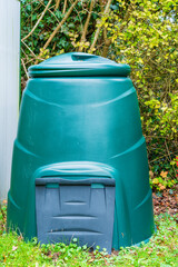 A green plastic composting bin for gardening waste to help crops grow