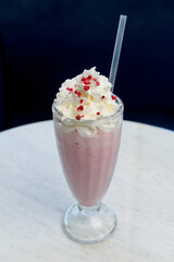 Strawberry milkshake with whipped cream and freeze-dried berries in a glass.