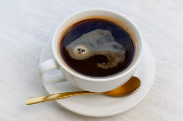 Aromatic strong Americano or espresso in a white cup with foam