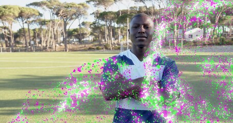 Standing soccer player in navy-and-white jersey facing camera on grass pitch, magenta-green effect