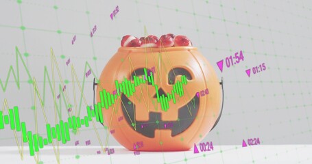 Displaying orange jackolantern bucket holding red candy on white table in studio, with green bars