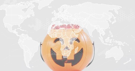 Fototapeta premium Displaying plastic orange jack-o'-lantern bucket center-front in studio, with world map overlay
