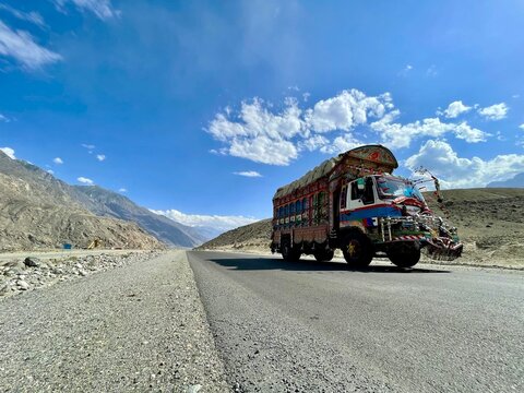 Karakoram Highway, Pakistan: a colorful, elaborately decorated "jingle truck" travels through towering mountains, showcasing South Asian culture along the historic Silk Road route.