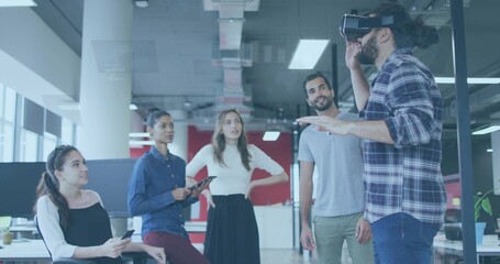 Gesturing man wearing plaid shirt and jeans testing VR headset in open-plan office, copy space