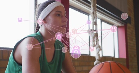 Sitting athlete in green jersey white headband studying court in gym with basketball rope pink data