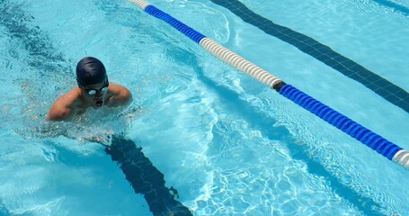 Swimming male swimmer stroking through outdoor lap lane, passing lane divider and wearing goggles