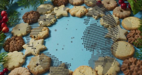 Displaying cookie wreath on pale-blue surface with fir sprigs red berries crumbs halftone overlay