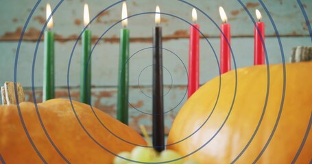 Naklejka premium Displaying kinara candleholder with 7 lit tapers burning on table, pumpkins, apple, wall overlay