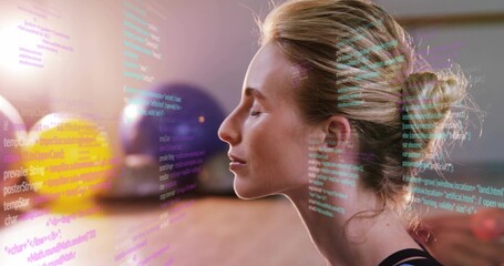 Sitting female meditating with eyes closed in studio, wearing dark tank, overlaid code, gym balls