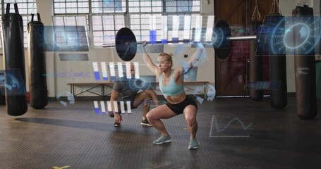 Lifting midadult woman in blue bra shorts holding barbell overhead squatting at gym with AR metrics