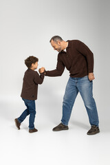 Playful arm wrestling between a father and his son in a bright outdoor setting