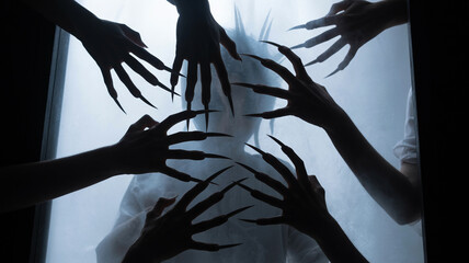 Spooky hands with long nails surround a person behind frosted glass surface